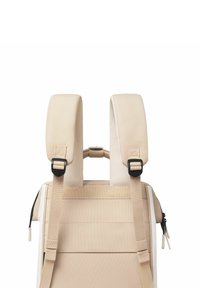 Beiger Rucksack mit gepolsterten Schultergurten, verstellbarer beiger Hardware und glatter Textur. Verfügt über einen Reißverschluss und vertikale Riemen auf der Rückseite.