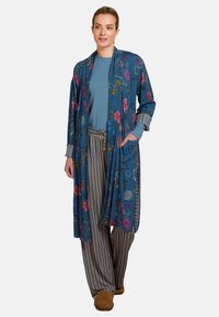 Long blue floral kimono jacket with a relaxed fit, featuring colorful flower patterns and stripes at the cuffs, paired with striped wide-leg pants.