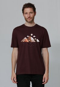 Bordeauxrotes Baumwoll-T-Shirt mit einem Bergmotiv in erdigen Farben, über dem Wolken und eine Sonne abgebildet sind. Mit kurzen Ärmeln und lockerer Passform.