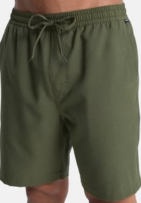 Ελιά πράσινα μαγιό σορτς κατασκευασμένα από ελαφρύ ύφασμα. Διαθέτουν ελαστική μέση με κορδόνι, πλαϊνές τσέπες και ομαλή υφή.