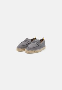 Grå espadrilles med en blød tekstiloverdel, flad espadrille-sål, dekorativ syning og tofarvet hæl i gul og navy.