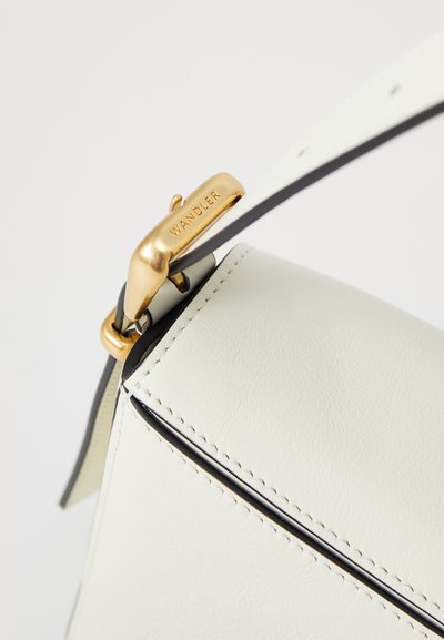 White leather handbag with a structured shape, highlighted by black stitching and a shiny gold clasp engraved with "WANDLER."