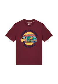 T-shirt bordeaux avec un graphique rétro d'une camionnette colorée, des planches de surf et le texte "VOYAGER ET SURFER À TRAVERS LE MONDE" en lettres majuscules bleu marine.