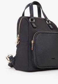 Zaino nero in una combinazione di tessuto liscio e pelle texturizzata. Presenta dettagli in oro, manici doppi e una tasca frontale con zip.