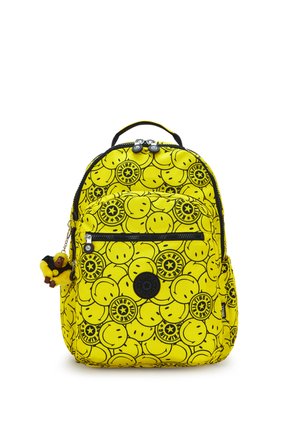 Sac à dos jaune vif avec un visage souriant noir et des logos d'étoiles, poche avant zippée et un petit porte-clés en peluche de singe attaché.