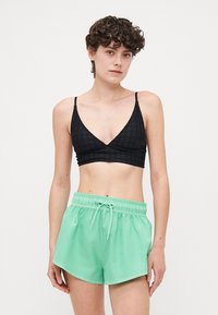 Fekete, textúrázott bralette V-nyakú kialakítással, párosítva mentazöld, húzózsinóros, könnyű anyagból készült sorttal.
