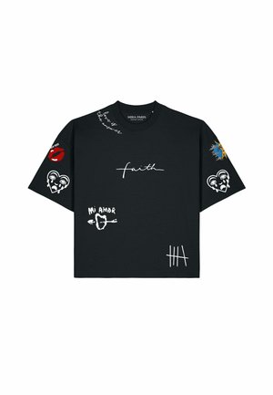 Homme portant un t-shirt noir oversize avec texte blanc "faith," graphismes de cœur et de soleil, "mi amor" avec flèche, et lunettes de soleil noires.