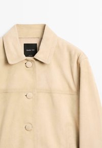 Beige ruskindjakke med dækkede knapper, krave og sidelommer, mærket "Massimo Dutti" indeni kraven.