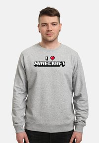 Felpa grigia realizzata in misto cotone. Presenta una grafica pixelata nera e rossa "I ❤️ MINECRAFT" sul davanti. Design classico con colletto a girocollo.