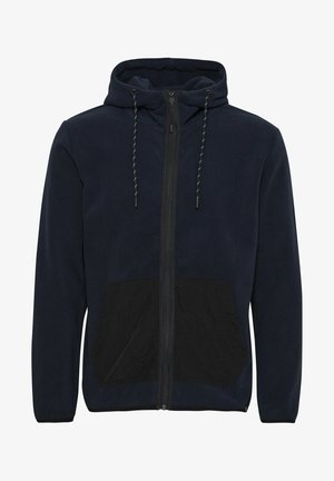 Granatowa polarowa kurtka z kapturem z czarną kieszenią z przodu, z zamkiem błyskawicznym oraz sznurkami z zielonymi akcentami na kapturze. Miękka faktura.