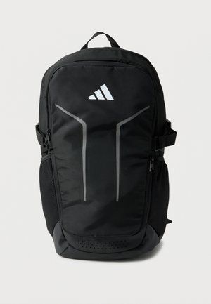 Fekete Adidas hátizsák két fényvisszaverő függőleges csíkkal, elülső cipzáras zsebbel, oldalsó hálós zsebekkel és felső fogantyúval.
