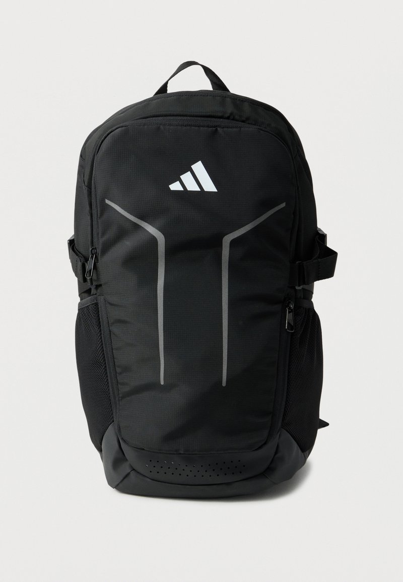 Μαύρο σακίδιο Adidas με δύο ανακλαστικές κάθετες ρίγες, μπροστινή τσέπη με φερμουάρ, πλαινές τσέπες από δίχτυ και χειρολαβή στην κορυφή.