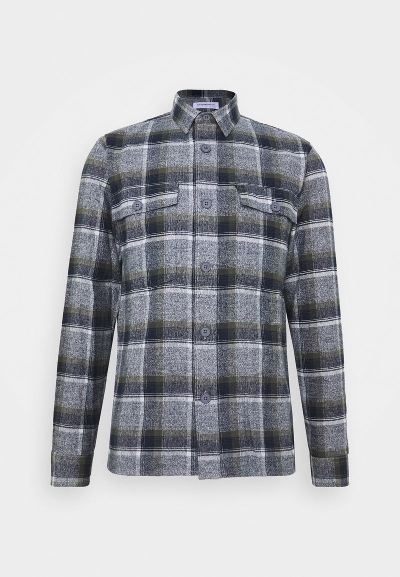 Chemise à manches longues boutonnée avec motif à carreaux vert, gris et blanc et deux poches poitrine à boutons.