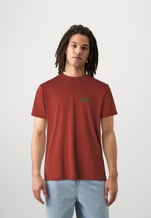 Czerwona koszulka z krótkim rękawem wykonana z bawełny, z okrągłym dekoltem. Posiada małe zielone logo na lewej piersi i ma luźny krój.