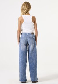 Lichtblauwe denim jeans met wijde pijpen en een vervaagde afwerking, vijf zakken ontwerp en een bruine leren label op de achterkant van de tailleband.