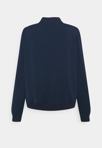 Námořnická modrá bunda s vysokým límcem, dlouhými rukávy a žebrovaným lemem. Hladká tkanina bez viditelných vzorů nebo kovových prvků.