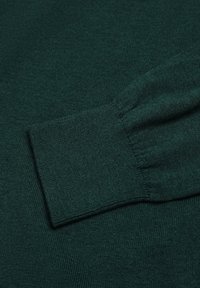 Donkergroen trui stof die een gladde textuur toont met ribbelmanchetten. Het ontwerp heeft een nauwsluitende mouw en een rechte lichaamsvorm.