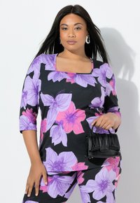 Kwiatowy top z fioletowymi i różowymi kwiatami na czarnym tle, z kwadratowym dekoltem, rękawami do połowy przedramienia, zestawiony z małą czarną torebką.