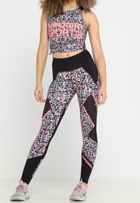 Set composto da top corto e leggings con una stampa leopardata rosa e nera, realizzato in tessuto elastico con pannelli in rete.