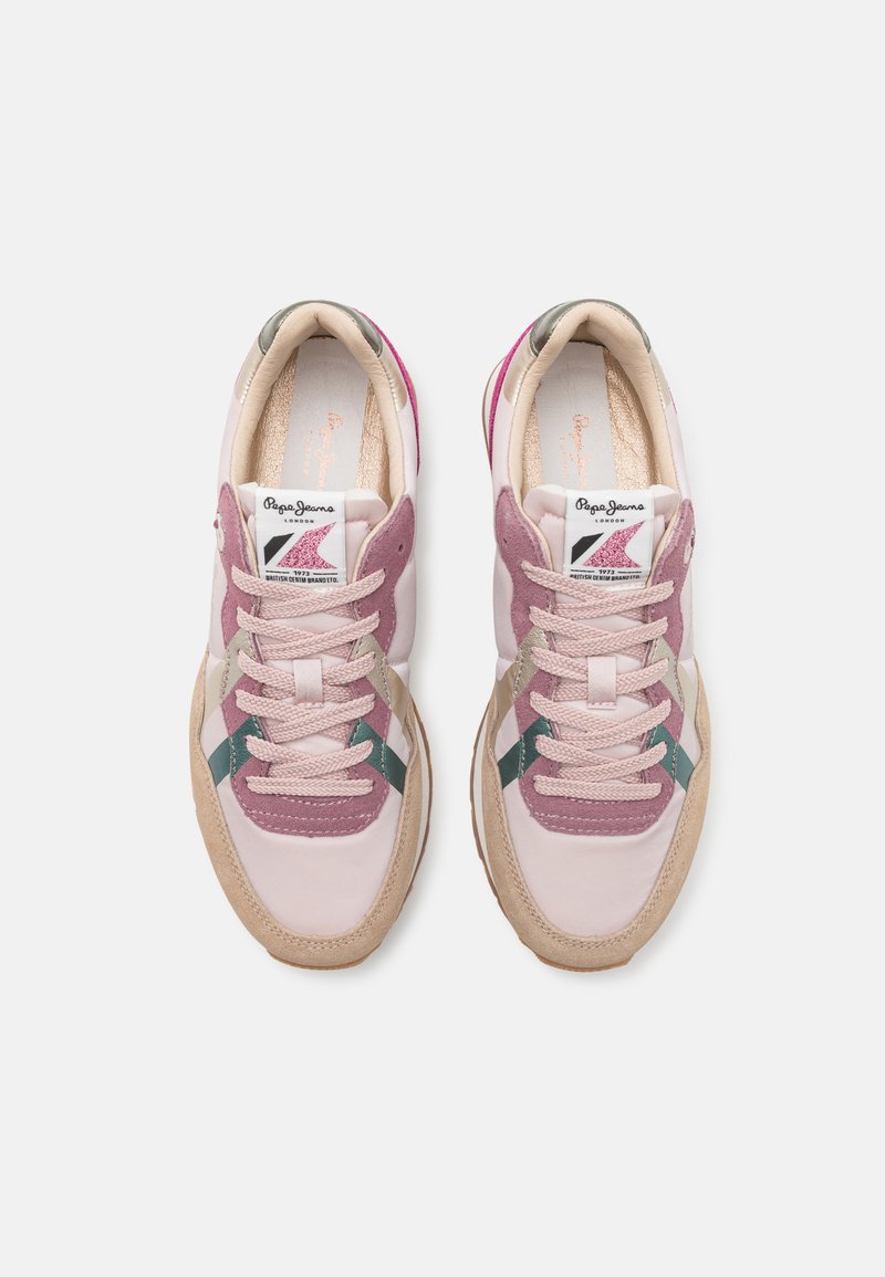 Helle rosa Sneaker mit Wildlederakzenten in Mauve, verfügt über einen grünen Streifen und eine strukturierte beigefarbene Gummisohle. Die Schnürsenkel sind hellrosa.
