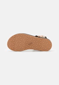 Suola di sandalo in gomma marrone con un motivo geometrico testurizzato e logo. La parte superiore presenta cinturini neri e beige con chiusure regolabili.