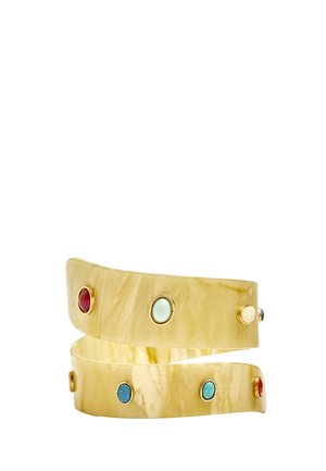 Zaokrąglona kremowa bransoletka typu mankiet z osadzonymi owalnymi kamieniami w kolorach czerwonym, niebieskim, białym i turkusowym, z których każdy oprawiony jest w złocone oprawki.