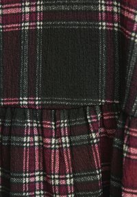 Abito a quadretti nero e bordeaux con parte superiore di texture e gonna arricciata. Presenta linee bianche nel motivo, enfatizzando il design a scacchi.