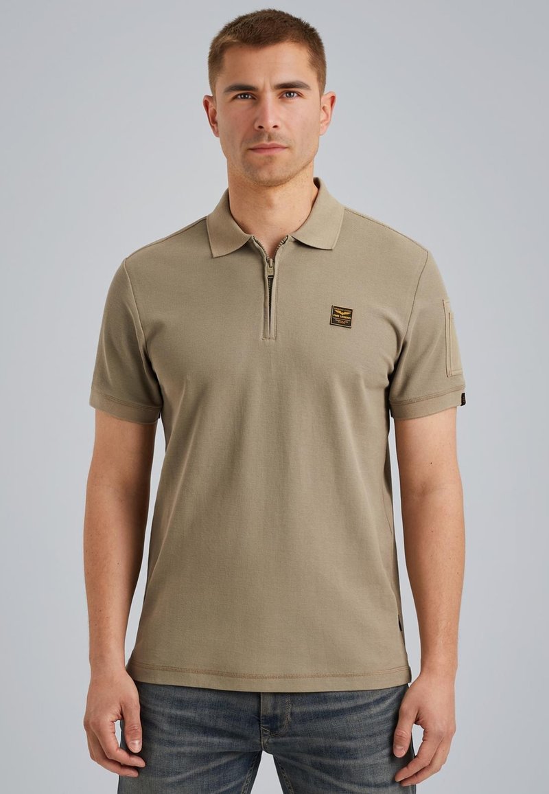 Khaki poloshirt met ritssluiting op de kraag, korte mouwen, geborduurd logo op de borst, rechte zoom en zijaccent. Glad katoen. 