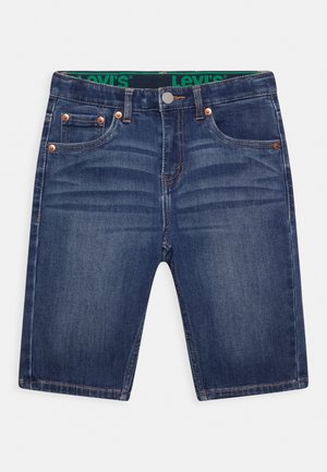 Dunkelblaue Denim-Shorts mit geradem Schnitt, ausgestattet mit kupferfarbenen Nieten und einem grünen Markenbund. Sauberes Finish mit minimalem Ausbleichen.