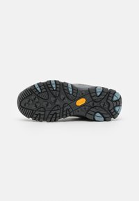 Svart gummiyttersåle med dype spor, blå akenter på lugs, med en teksturert overflate og et Vibram-logo i midten.