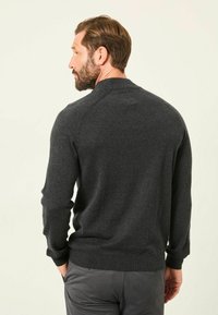 Dunkelgrauer Strickpullover mit rundem Kragen und gerippten Bündchen. Weiche Textur und taillierter Schnitt, von hinten gezeigt mit minimalem Design.