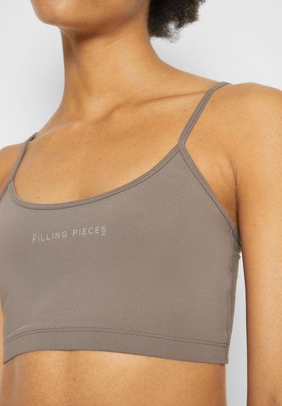 Sutiã desportivo castanho feito de material elástico, com alças finas e decote arredondado, apresentando o logótipo "Filling Pieces" em cinza claro.