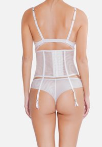 Ensemble de lingerie blanche comprenant un corset transparent avec fermeture à crochets, des bretelles ajustables et des culottes taille basse assorties avec des accents en satin.