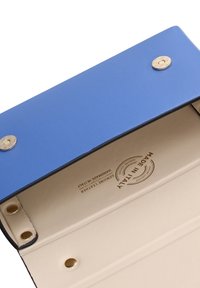 Portafoglio in pelle blu e beige aperto, che mostra bottoni a pressione in metallo e un timbro in pelle "Made in Italy" all'interno.