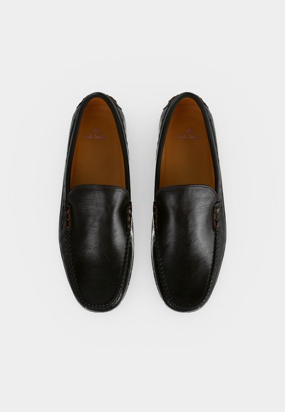 Ζευγάρι μαύρα δερμάτινα loafers χωρίς κορδόνια με στρογγυλεμένες τετράγωνες μύτες και ταμπά εσωτερικά μέρη, απόψη σε λευκό φόντο.