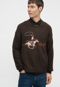 Καφέ πλεκτό πουλόβερ με γραφικό ενός καουμπόι πάνω σε άλογο. Διαθέτει ριμπ μανίκια και στρίφωμα, με υφή υφάσματος και διακριτά αντίθετα χρώματα.