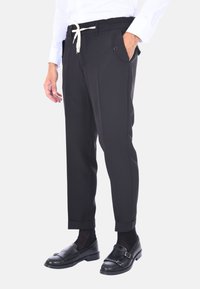 Pantaloni neri a sigaretta con vita alta regolabile tramite coulisse, tasche laterali e orli arrotolati. Realizzati in tessuto liscio, con una leggera lucentezza.