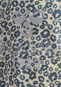 Leopardmönstrad tyg i beige och marinblått, med silverfärgade texturerade grafik av en logotyp och året "1923" i fet stil.