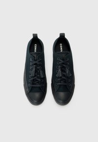 Para czarnych niskich trampków Converse z czarnymi gumowymi czubkami, czarnymi sznurowadłami i uchwytami na białym tle.