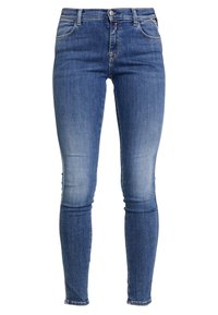 Vaqueros ajustados en denim azul medio con desvanecimiento en degradé, diseño estándar de cinco bolsillos, cierre de botón metálico y ligero deshilachado en el dobladillo.