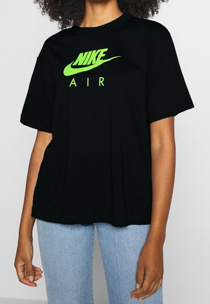 T-shirt en coton noir à manches courtes, avec un logo Nike vert néon et le texte "AIR" sur la poitrine. Coupe décontractée.