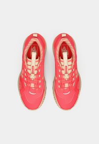 Pair of bright red and beige Vans MTE sneakers with elastic toggle laces and patterned inner lining, viewed from above on a white background.
