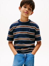 Tricou din bumbac, cu mânecă scurtă, de culoare bleumarin, cu dungi orizontale maro, alb și albastru. Croi lejer, completat de blugi din denim decolorat.
