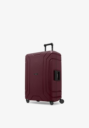 Grande valigia rigida color mogano con quattro ruote, manico telescopico esteso e serratura a combinazione laterale integrata.