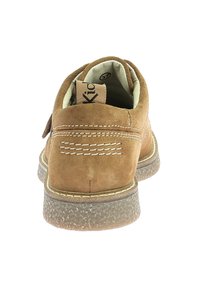 BROWN SUEDESCHOEN MET EEN RONDE VORM, RUBBEREN ZOOL, WITTE STIKSELDETAILS EN EEN LABEL IN DE BINNENKANT MET DE NAAM "Kick." GETEXTUREERD OPVLAK.