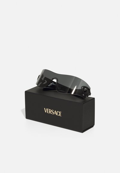 Ochelari de soare negri, supradimensionați, cu un design curbat, având lentile întunecate și accente negre, prezentați pe o cutie neagră etichetată "VERSACE" în aur.