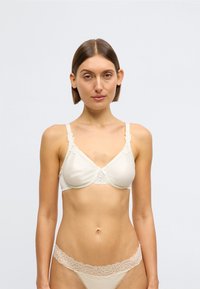 Sutiã em tecido creme com detalhes em renda e um laço decorativo ao centro. Apresenta alças finas ajustáveis e um design liso, sem forro.