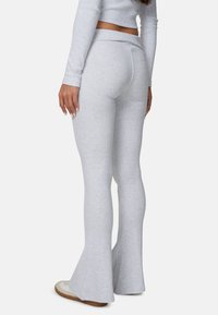 Szare dzwony z gładkiej tkaniny i średnim stanem w pasie. Posiadają subtelne detale szwów oraz dopasowany krój.