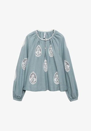 Svetlo modra bluzica z dolgimi rokavi, nabranim ovratnikom in dekorativnimi belimi čipkastimi listnatimi vzorci. Ima gumbnico spredaj.