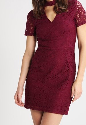 Weinrotes Spitzenkleid mit kurzen Ärmeln, V-Ausschnitt und aufwändigem Blumenmuster, entworfen für eine figurbetonte Silhouette.